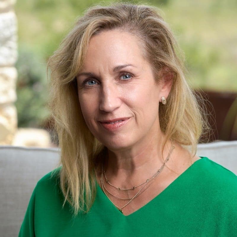 Gretchen Howell in a green shirt sitting on a couch.