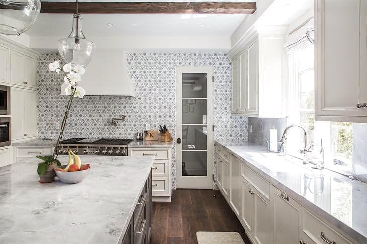 A white kitchen with marble counter tops.