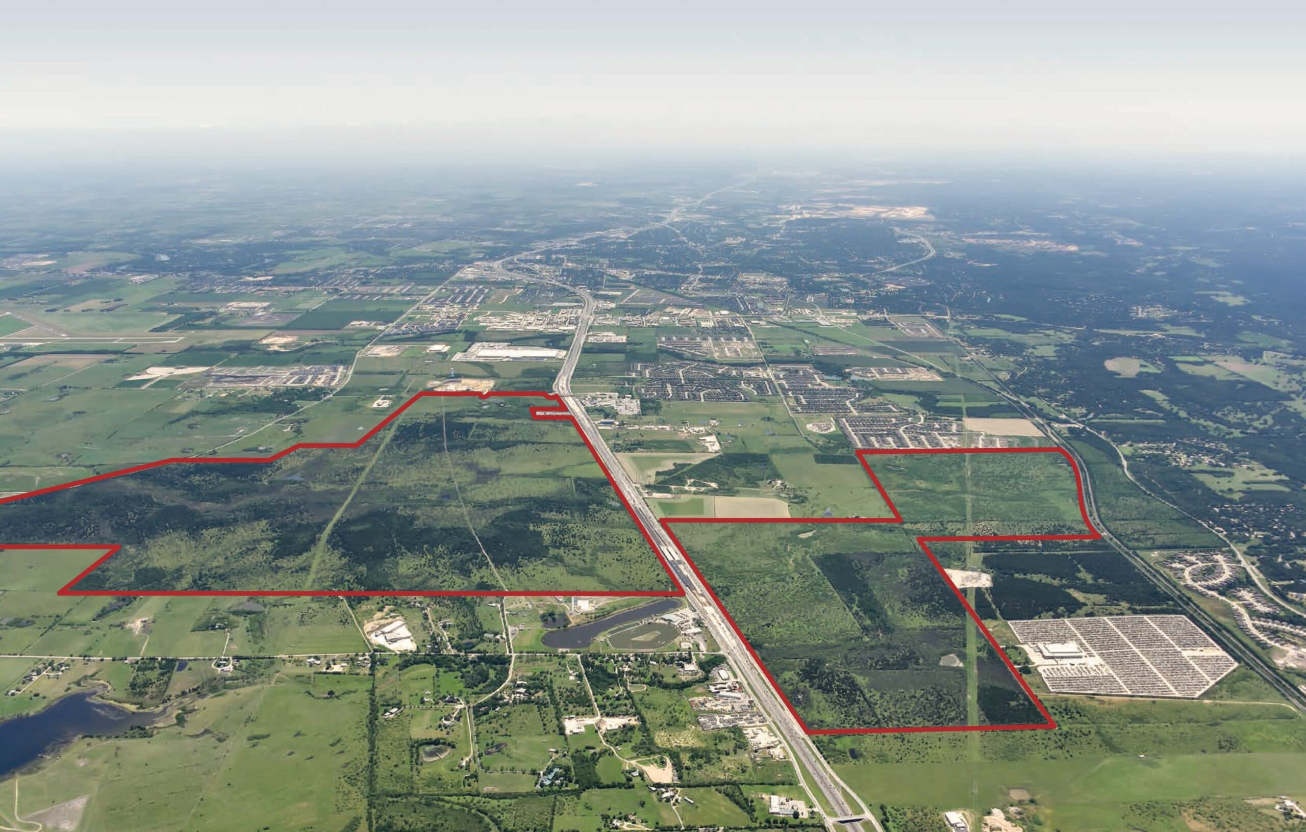 An aerial view of a large area of land with red lines outlining the Mayfair perimeter
