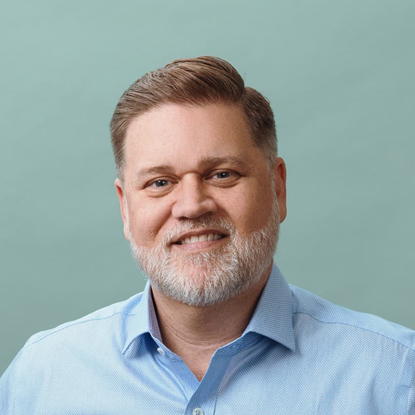 A man in a blue shirt with a beard.