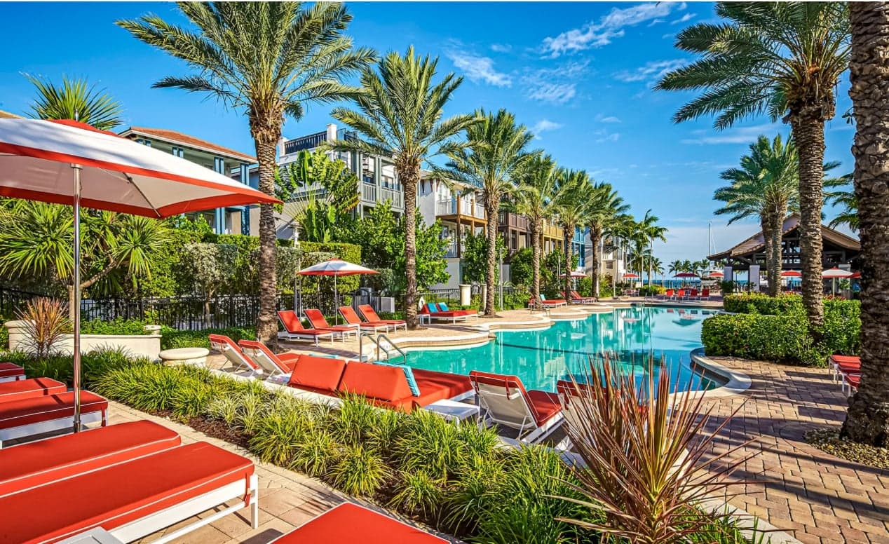 A pool with red lounge chairs and umbrellas at Marlin Bay