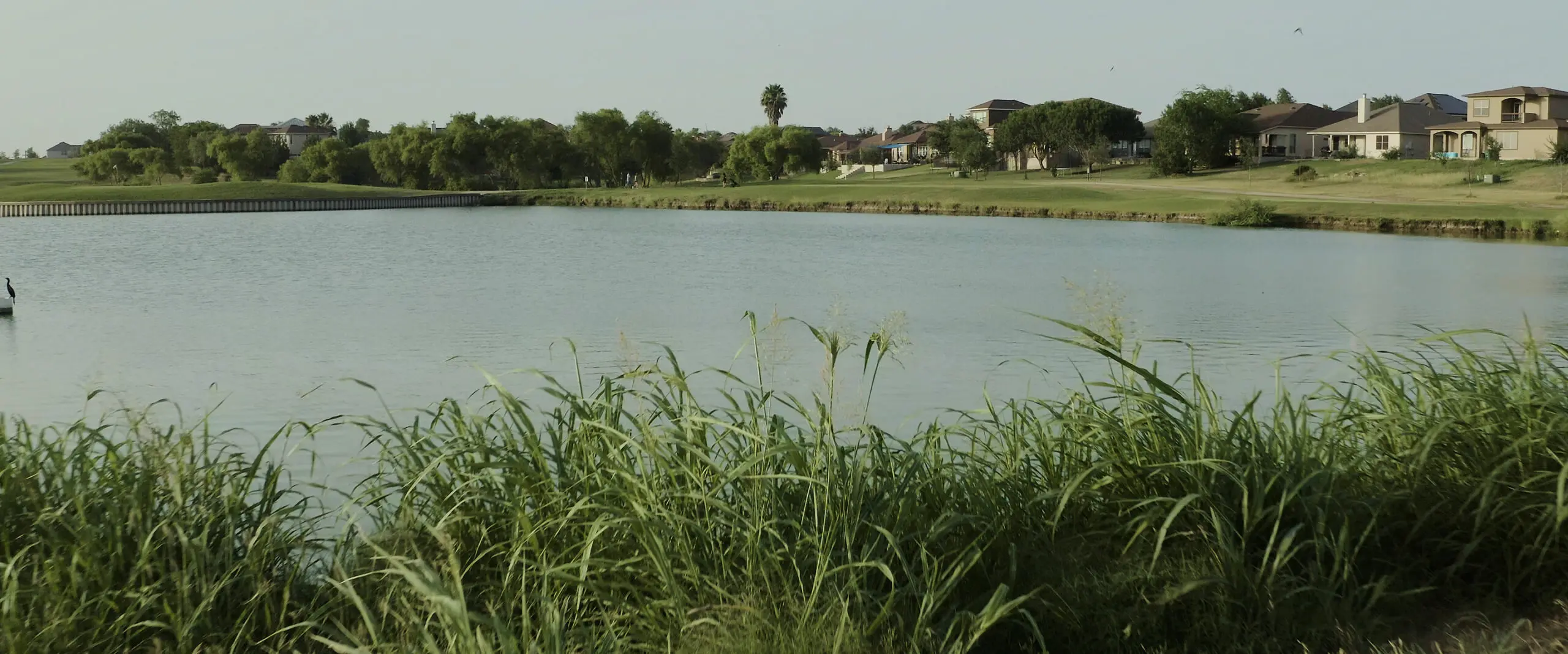 A golf course with a pond in the background at Mission del Lago