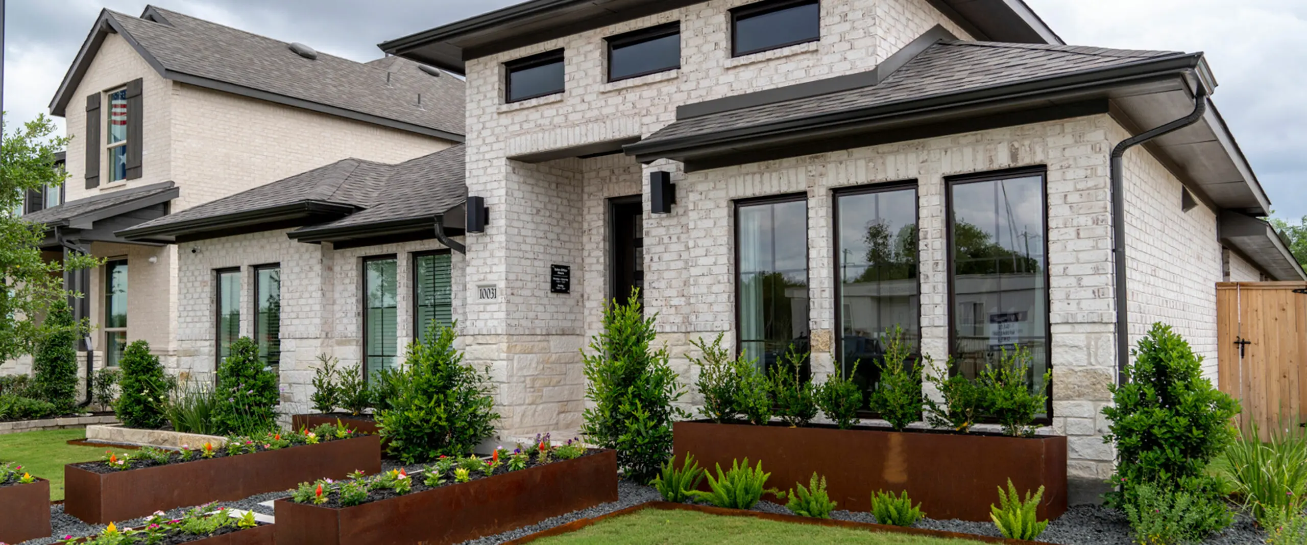 A home with many windows and a large front yard with planters.